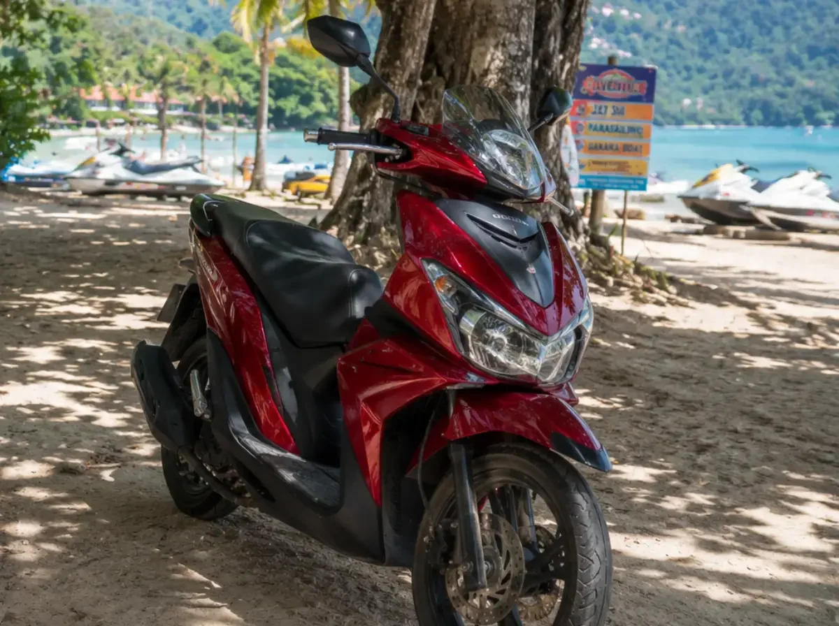 Ein Tourist fährt sichtlich unsicher mit einem gemieteten Motorroller durch den dichten und chaotischen Verkehr in Thailand