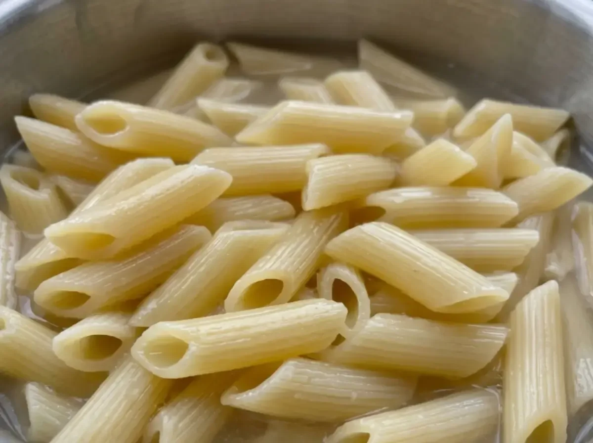 Gekochte Penne in einem Topf mit Kochwasser, Nahaufnahme.