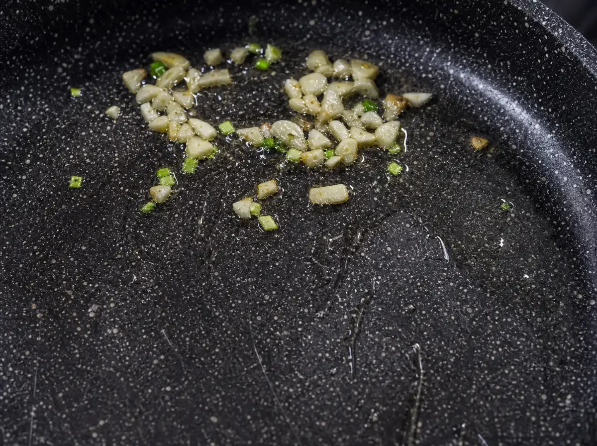 Knoblauch wird in Öl angebraten als erster Schritt für Gebratene Gurke mit Ei nach thailändischer Art.