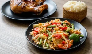 Ergebnis für ein authentisches Som Tam Rezept: Thailändischer Papayasalat, traditionell serviert mit gegrilltem Hähnchen und Klebreis.