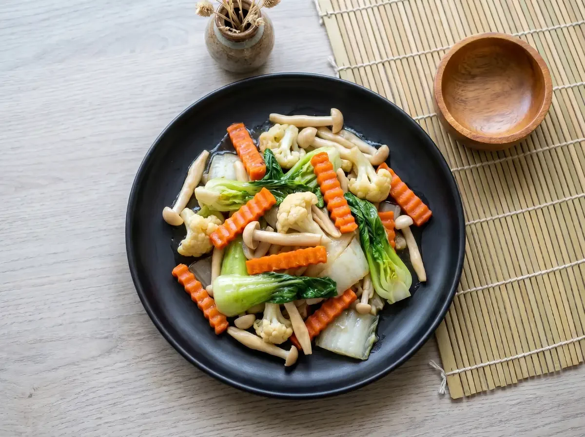 Pad Pak Ruam Mit auf schwarzem Teller in der Draufsicht mit Pak Choi, Karotten, Blumenkohl und Pilzen