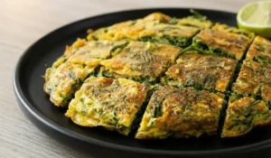 Traditionelles Thai Cha-Om Omelett Rezept, saftig gebraten und angerichtet auf einem schwarzen Teller