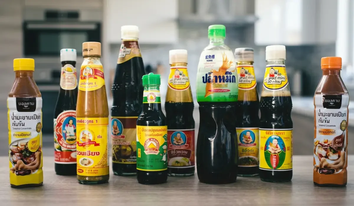 Thai Saucen in verschiedenen Flaschen auf Küchentisch, darunter Fischsauce, Sojasauce und Tamarindensauce