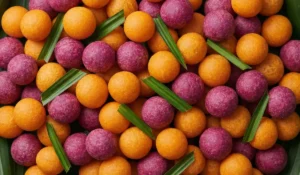 Eine Nahaufnahme: Frittierte Thailändische Süßkartoffel-Bällchen in leuchtendem Orange und kräftigem Lila, hübsch angerichtet und dekoriert mit grünen Pandanblättern.