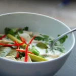 Vegane Tom Kha Suppe in einem weißen Suppenteller mit Löffel