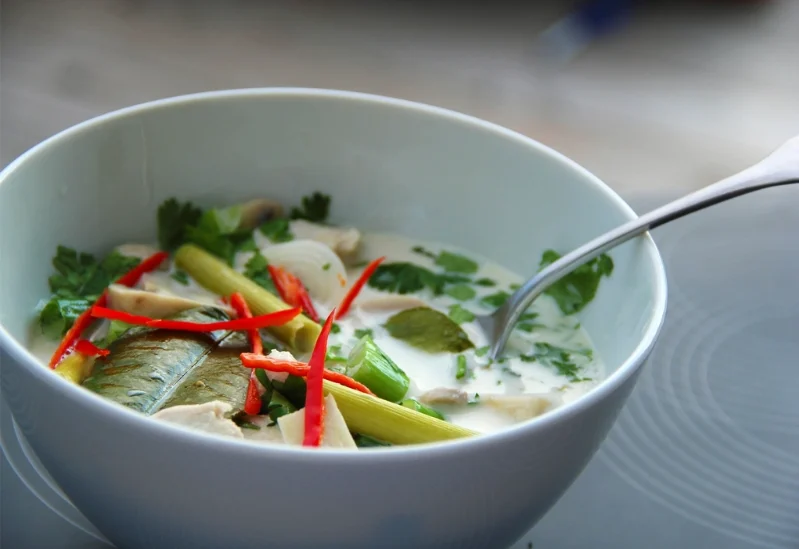 Vegane Tom Kha Suppe in einem weißen Suppenteller mit Löffel